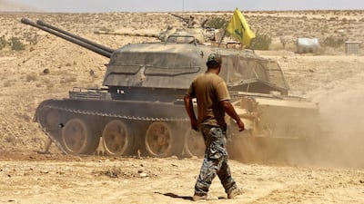 A fighter walks past a tank bearing a Hizbollah flag in eastern Syria on August 28, 2017. The US government issued new financial rewards for two Hizbollah leaders on Tuesday. Louai Beshara / AFP