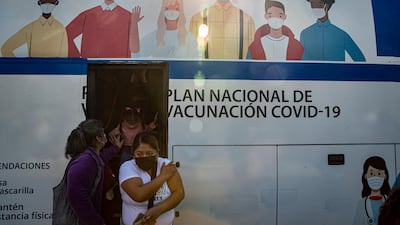 Women leave a bus being used as a Covid-19 vaccination clinic in Santiago, Chile. AP Photo
