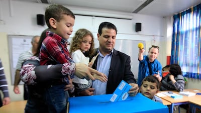 FILE - In this March 17, 2015 file photo, Ayman Odeh, head of the Joint List, an alliance of four small Arab-backed parties accompanied by his family, casts his ballot in Haifa, Israel. Israel's four Arab political parties are announcing a merger ahead of September elections, a move that aims to boost voter turnout among the country's Arab minority. The Palestinian nationalist Balad party announced late Sunday, July 28, 2019, that it would join a reunited Joint List of Arab parties, months after infighting fragmented the political alliance. (AP Photo/Mahmoud Illean, File)