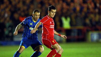 AFC Wimbledon's Barry Fuller, left, vies for the ball with Liverpool's Philippe Coutinho during their FA Cup match on Monday night. Sean Dempsey / EPA