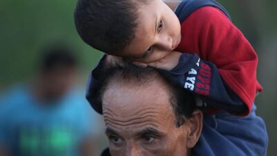 A migrant boy rests on the head of a man carrying him along the railway track at the Hungarian border with Serbia. Migrants are rushing to the border fearing the borders will be sealed off before the official closure of midnight on Monday.