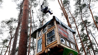 An activist uses a rope to climb over a tree house during a protest against deforestation, part of plans to extend the Tesla Gigafactory, in Gruenheide, near Berlin. EPA
