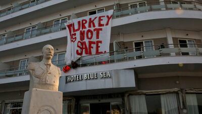 A banner reading: ‘Turkey is not Safe’ hangs from a hotel as migrants are escorted by Frontex officers to ferries in the port of Mytilene, Lesvos island, Greece. Orestis Panagiotou / EPA