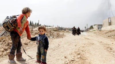 Syrian children wait for other civilians to catch up as they pass through a regime-controlled corridor opened by government forces in Hawsh Al Ashaari, east of Hamouria, on March 15, 2018. Louia Beshara / AFP