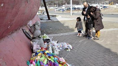 A family prays for the victims of the March 11, 2011 earthquake and tsunami in front of the 330-tonne fishing vessel Kyotoku Maru No 18 which was flung 800 metres inland from Kesennuma port by the tsunami in Kesennuma, Miyagi Prefecture on Saturday. Shizuo Kambayashi / AP Photo