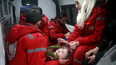 Men and women from the Red Cross treat a baby in the eastern Ghouta region of Syria in December 2017. Abdulmonam Eassa / AFP
