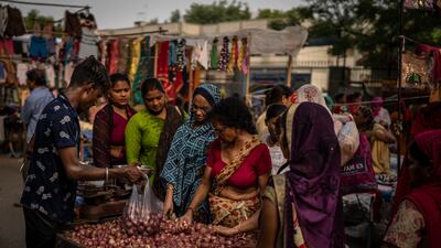 A roadside vendor packs onions in plastic bags as women shop at a weekly market in New Delhi, India. AP