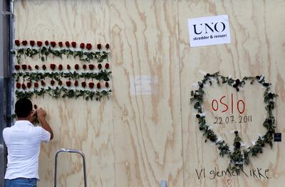 A man arranges flowers next to a graffiti marking a bomb attack in the centre of Oslo on July 28, 2011, where Anders Behring Breivik killed 76 people. Reuters