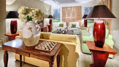 The tawny browns of the furniture and buttery creams of the shutters make the area tranquil among the brighter hues of greens and yellow for the sofas, thereby allowing the owner's vibrant but orderly personality to be fully expressed. The custom side tables complement the main dining space