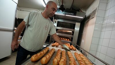 A baker takes baguettes out of an oven at a bakery in Versailles. The French baguette has been given Unesco World Heritage status. AP