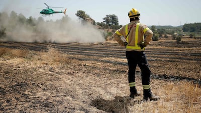 A firefighter looks at an helicopter as they try to extinguish a fire near Flix. AFP
