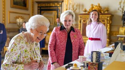 Queen Elizabeth II views a display of enamelware and china in the White Drawing Room at Windsor Castle on Thursday, to commemorate the 70th anniversary of British craftwork company, Halcyon Days. AP Photo