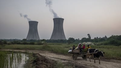 A cattle-pulled cart passes the central chimneys of the coal-fired NTPC Dadri Power Plant in Gautam Budh Nagar district, Uttar Pradesh, India. The South Asian state relies on coal for about 70% of electricity generation. Bloomberg