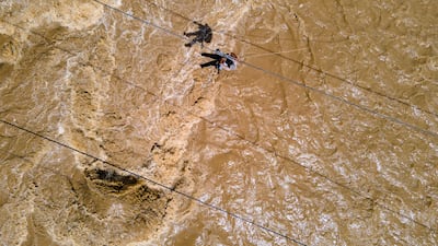 People use ropes to cross a river swollen by flash floods in Indonesia's Aceh province. AFP