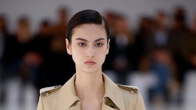 A hard, moulded armour-like dress at Loewe womenswear spring/summer 2023, decorated with flowers and worn under a truncated trench coat. Getty