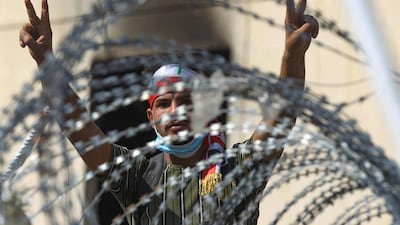 An Iraqi protester flashes the victory sign from behind barbed wire near Baghdad. AFP