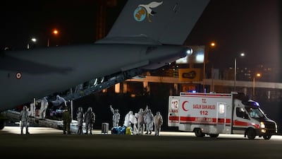 Turkish, Azeri and Georgian evacuees dressed in protective suits and wearing masks leave a Turkish military cargo plane as they are flanked by medical workers upon their arrival from China's Wuhan in Ankara, Turkey. Reuters