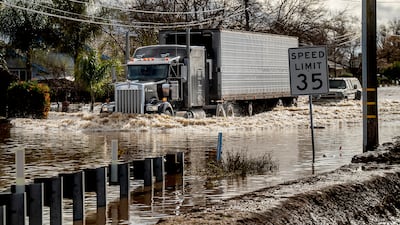 A lorry barely makes it through floodwaters in Merced as storms continue to batter California on Tuesday. AP
