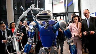 German Chancellor Friedrich Merz, right, steers DLR's humanoid walking robot TORO, watched by Minister for Research, Technology and Space Dorothee Baer, second right, at the launch of the country's High-Tech Agenda in Berlin. AFP