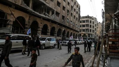 People walk along an aid convoy of trucks as they arrive in Douma, in Eastern Ghouta, Syria, on March 5, 2018. Mohammed Badra / EPA