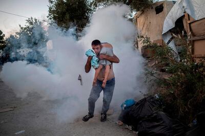 A man holds a boy during clashes with police outside the refugee camp of Moria. AFP