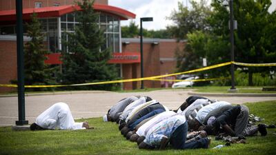Mohammed Omar, left, the executive director of the Dar Al Farooq Islamic Centre in Bloomington, Minnesota, leads afternoon prayers outside the police tape set up around the centre following a bomb attack on August 5, 2017. Aaron Lavinsky / Star Tribune via AP