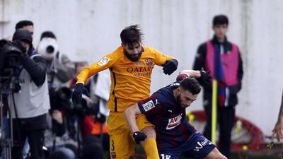 Barcelona defender Gerard Pique, left, fights for the ball with Eibar defender Borja Baston. Javier Etxezarreta / EPA