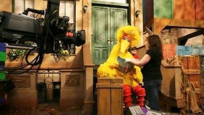 Michelle Hickey, a Muppet wrangler, helps Big Bird hold a book during a rehearsal of Sesame Street in New York.