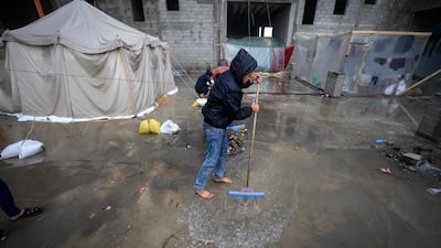 A Palestinian boy attempts to push water away from his tent in a camp in Rafah, where many civilians are sheltering amid continued fighting between Israel and Hamas. AFP