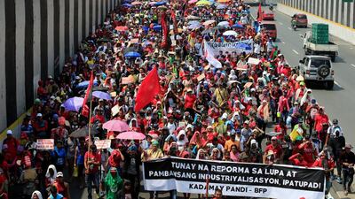 Filipinos from various workers’ groups hold a banner which reads “implementation of national industrialisation and real land reform” during a march in Manila. Romeo Ranoco / Reuters