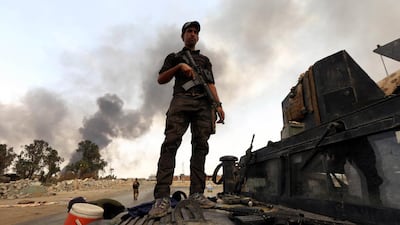 A member of the Iraqi government forces stands on a military vehicle as smoke billows from oil wells, set ablaze by ISIL militants before fleeing the oil-producing region of Qayyara. Safin Hamed/AFP Photo