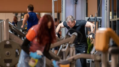 A member of staff cleans gym equipment as gym members return to work out at David Lloyd health club in Leicester. AP Photo