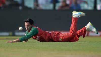 Bangladesh’s Arafat Sunny dives to stop the ball off his own bowling. ( AFP / Dibyangshu SARKAR)