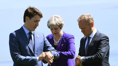 Canadian Prime Minister Justin Trudeau, British Prime Minister Theresa May and the President of the European Council Donald Tusk check their watches after a group photo at the G7 Summit in La Malbaie, Quebec, Canada. Saul Loeb / AFP