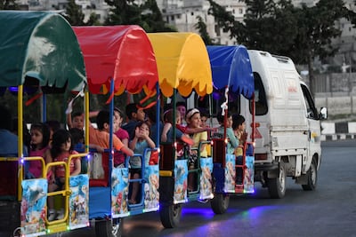 Children ride in carts through a street in the Syrian town of Ariha in the rebel-held north-western Idlib province. AFP