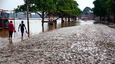 People walk on a muddy road after flood waters receded in Allahabad, India. AFP