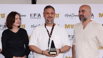 Ahmed Amer, centre, receives an award on stage.