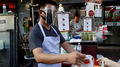 A man wearing a protective face mask and a visor sells street food in Chinatown. Reuters