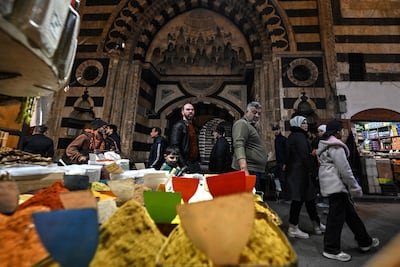 Syrians walk past a shop displaying spices at a market in the Old City of Damascus. AFP