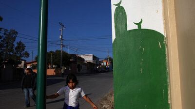 A young girl on her way home from Catholic school plays near the entrance of the Masjid El-Noor in Rosarito, Mexico.