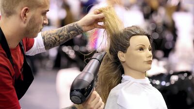 A stylist competes in the hairdressing category on the first day of WorldSkills at Abu Dhabi National Exhibition Centre. Chris Whiteoak / The National