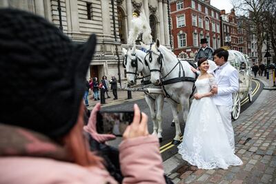 A couple pose for wedding photos with white horses and a carriage in Westminster, in London. Getty Images