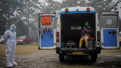 A medical worker wearing personal protective equipment stands next to a patient suffering from Covid-19. Reuters