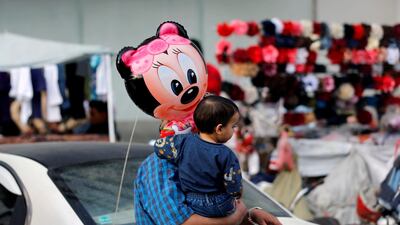 A man carries his son who holds a balloon outside a shopping centre in Sanaa. Reuters