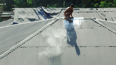 A villager cleans volcanic ash from the roof of his home. AFP