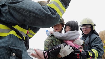 A handout photo released by the Military News Agency shows Taiwanese soldiers holding a young girl resuced from a collapsed building in Tainan, south Taiwan. Military News Agency / EPA