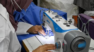 A factory worker stitches a zipper into a uniform. Finbar Anderson