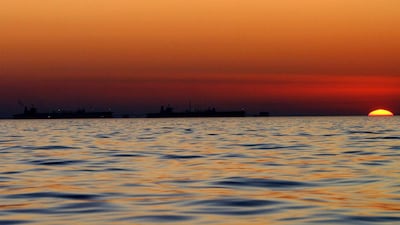 The sun sets off to the side of two oil tankers, as they fill up at the Al Basrah Oil Terminal, off the Iraqi Coast Line, February 10, 2004, The Arabian Gulf. Bloomberg