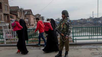 Kashmiri women carry children and walk past an Indian Paramilitary soldier standing guard on a bridge in central Srinagar, Indian controlled Kashmir, Thursday, February 20, 2020. AP