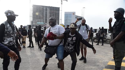 Journalist Abisola Alowode, who was mistaken for a protester, is arrested by police officers during a rally to commemorate the one-year anniversary of EndSARS. AFP